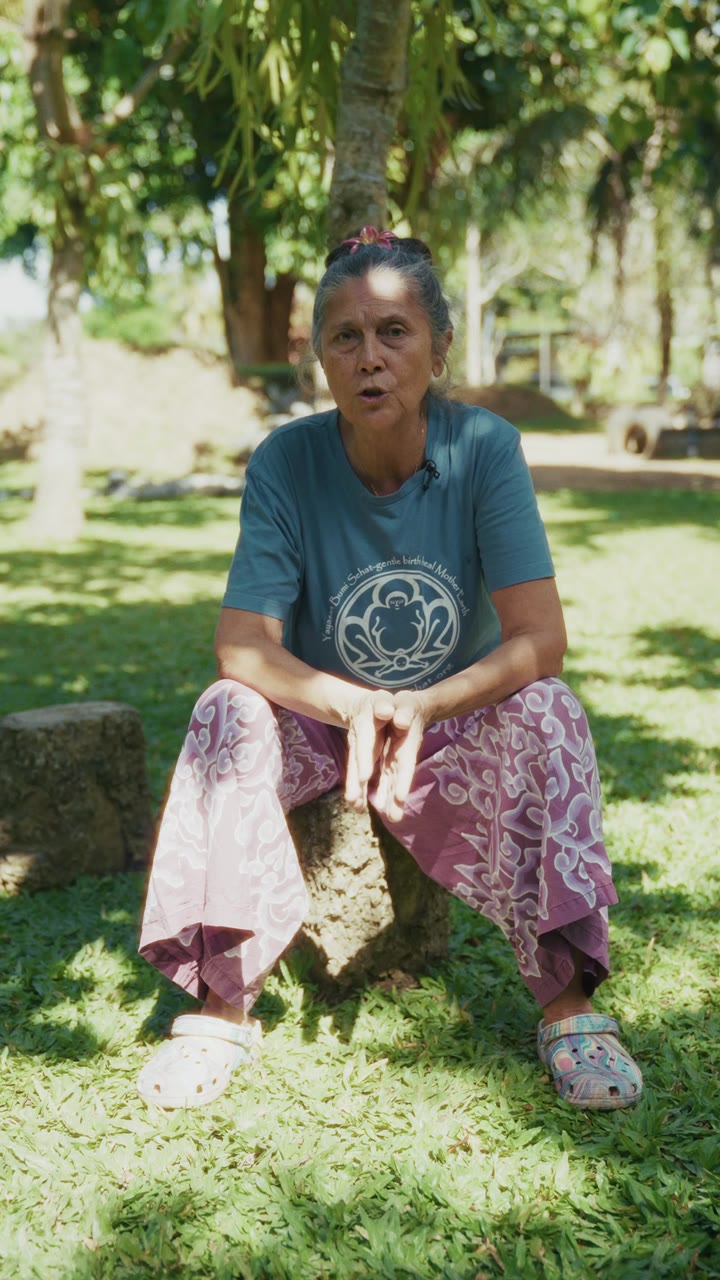 A birth worker seated on a tree stump, speaking