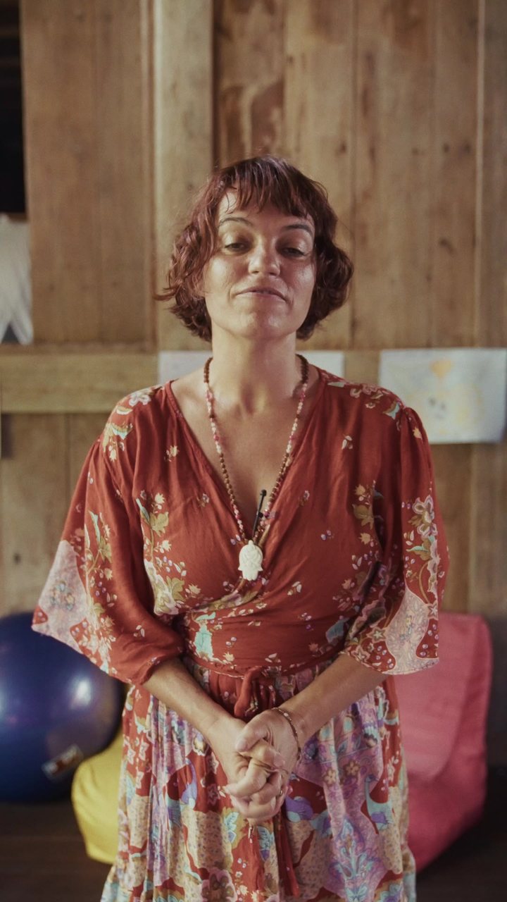 A doula in a red dress under a wooden roof