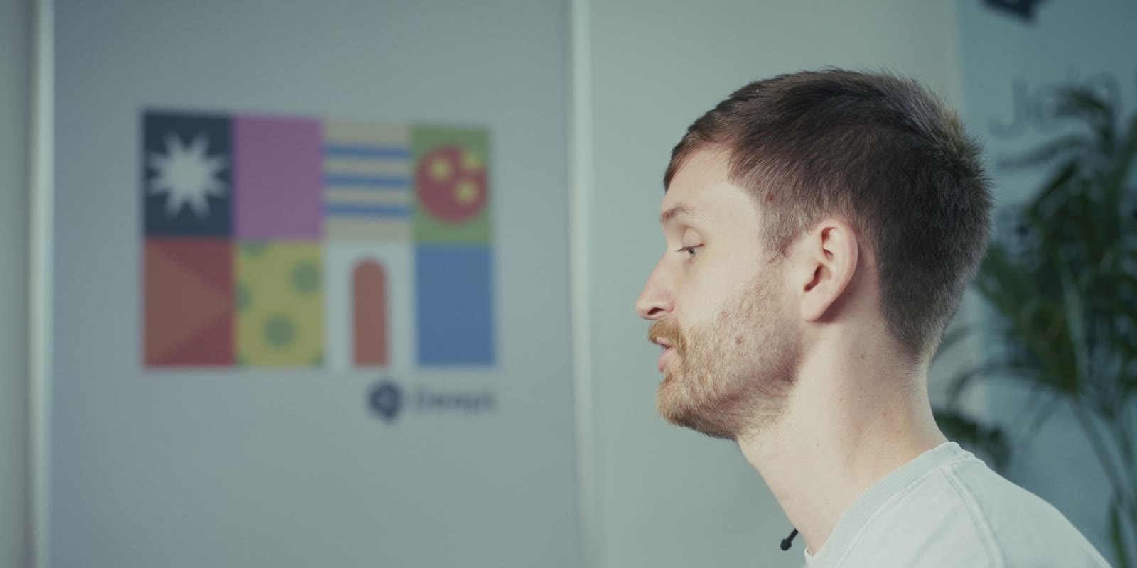 An engineer in profile in front of a DeepL poster