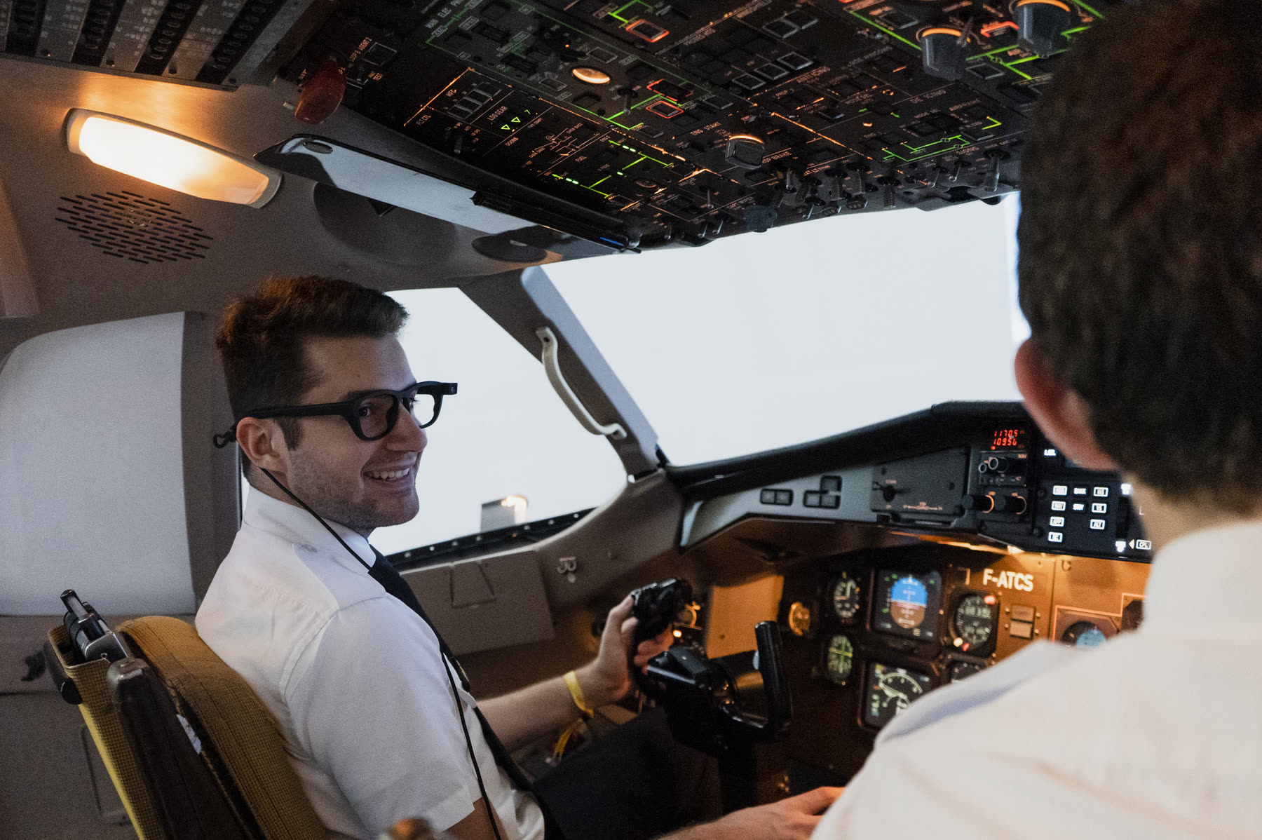A student pilot smiling at the controls in the cockpit