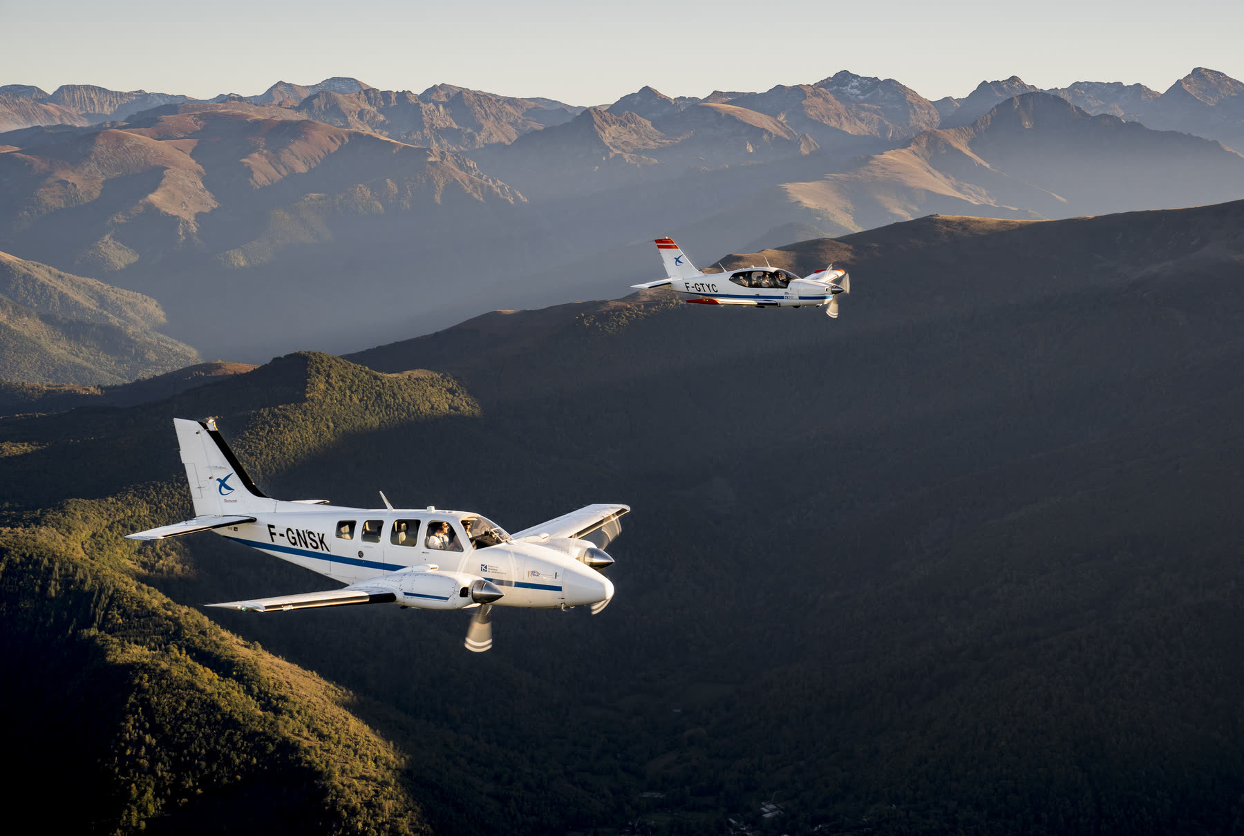 Two training aircraft in formation over the mountains