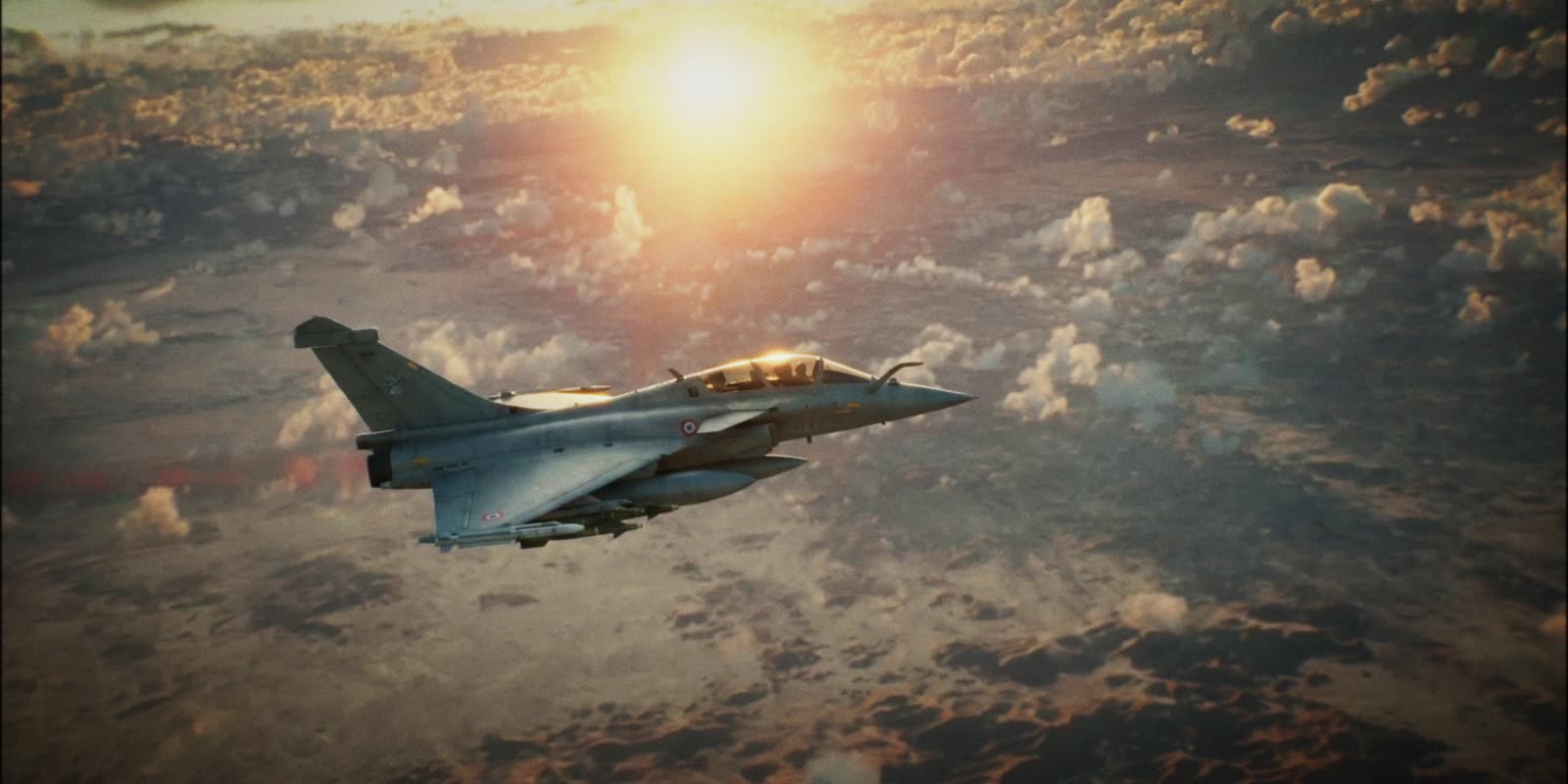 A fighter jet above the clouds at sunset